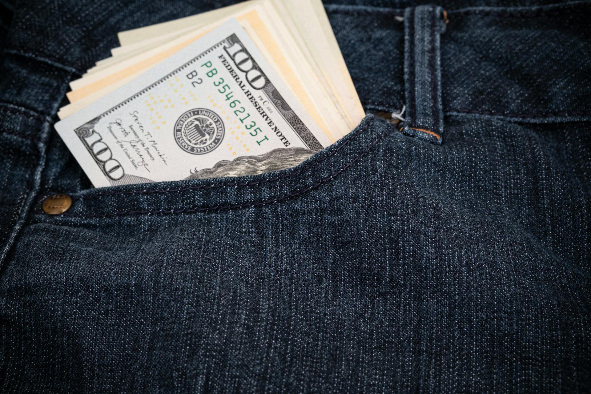 Several 100 us dollar bills in the pocket of jeans close up