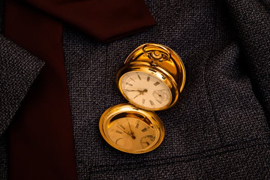Antique gold pocket watch placed on textured suit fabric, exuding elegance and classic style.