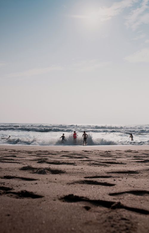 Free Children enjoy playing in the waves on a sunny, sandy beach day. Stock Photo