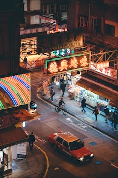 从高处俯瞰夜间繁忙的城市街道，霓虹闪烁，人流车流不息