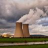 Dark, stormy clouds gather over the cooling towers of a nuclear power plant.