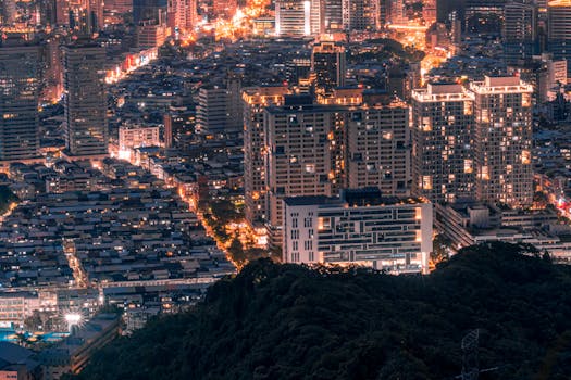 A vibrant aerial view of a modern cityscape with skyscrapers illuminated at night.