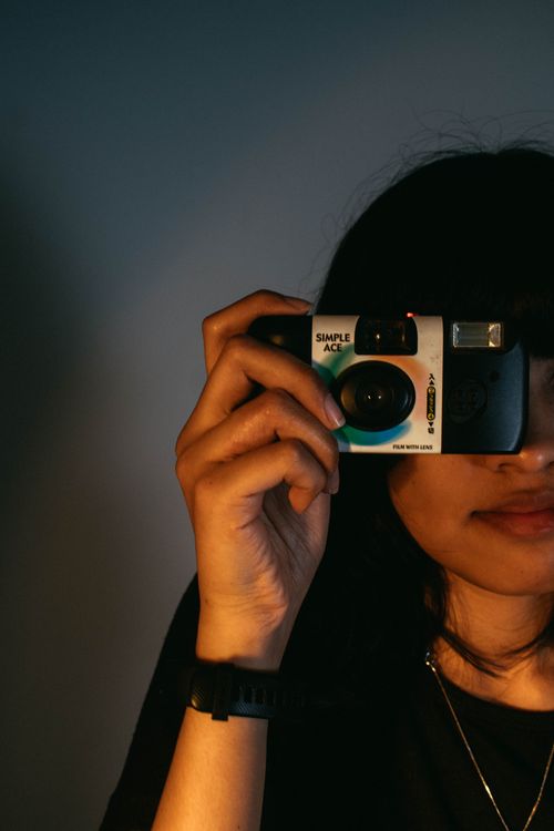 Free Woman with long hair holding a vintage camera, evokes a retro feel. Stock Photo
