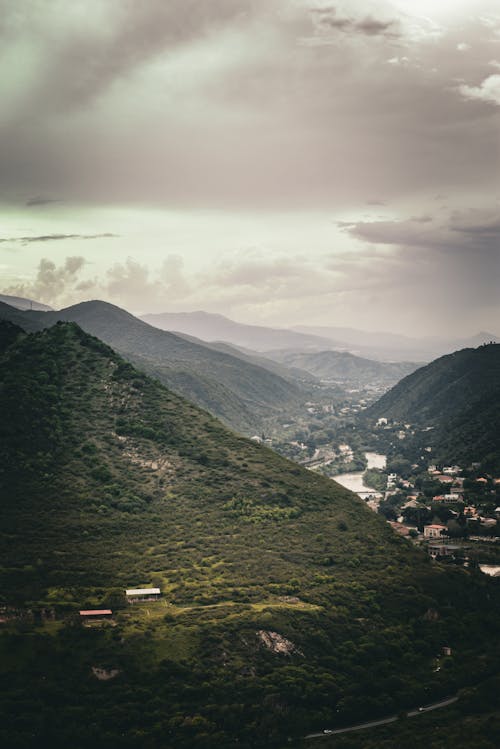 Aerial View of Mountains and Houses in a Valley under a Cloudy Sky 