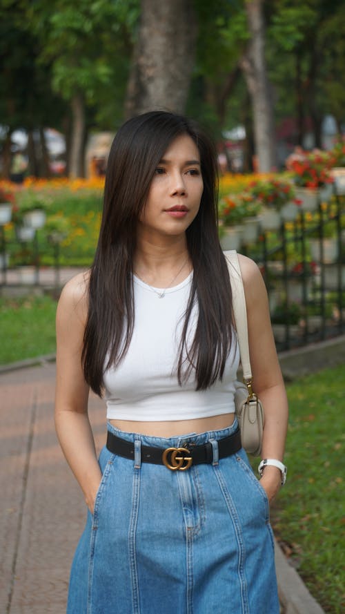Young Brunette in a Fashionable Outfit in a Park in Summer 
