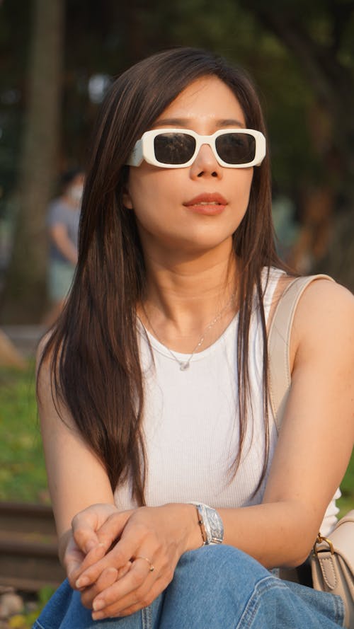 Young Brunette Wearing Sunglasses in a Park in Summer 