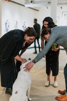 Group of adults interacts with a bulldog inside an art gallery setting, showcasing warmth and companionship.