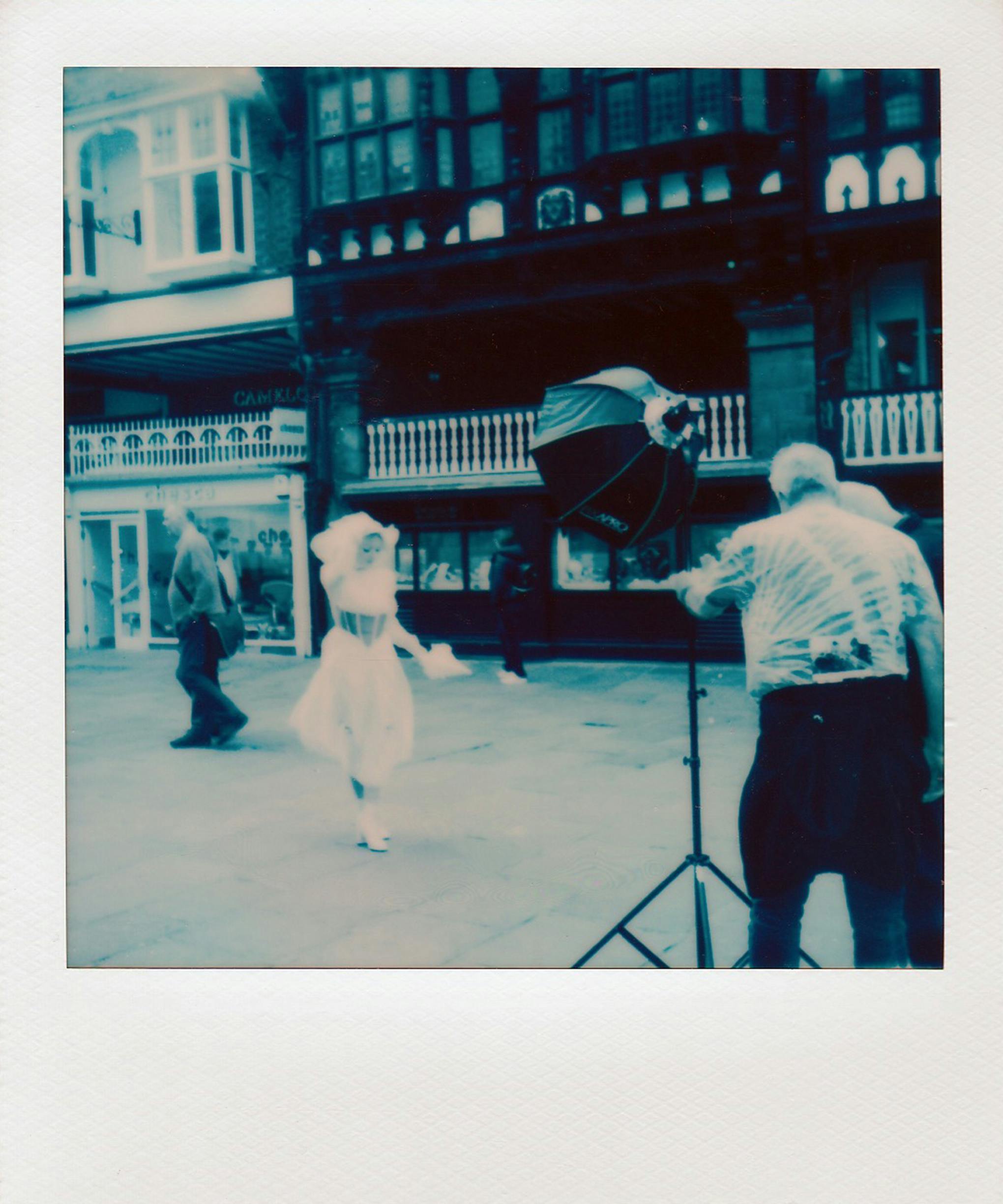 A vintage style street photo capturing a photographer and a model in a retro setup.