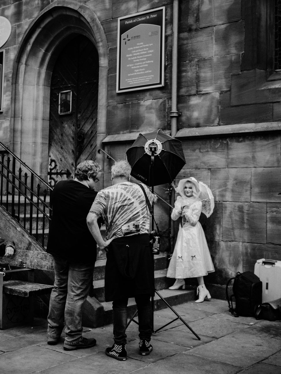 Black and white photo of a vintage-themed photo shoot on a city street outside a church.