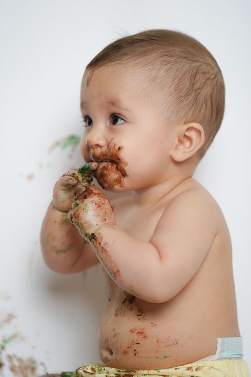 Free Cute baby with chocolate-covered face enjoying a treat in a studio shot, capturing childhood innocence. Stock Photo