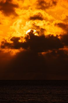 A stunning sunset with dramatic clouds over the ocean horizon, creating a vivid seascape.