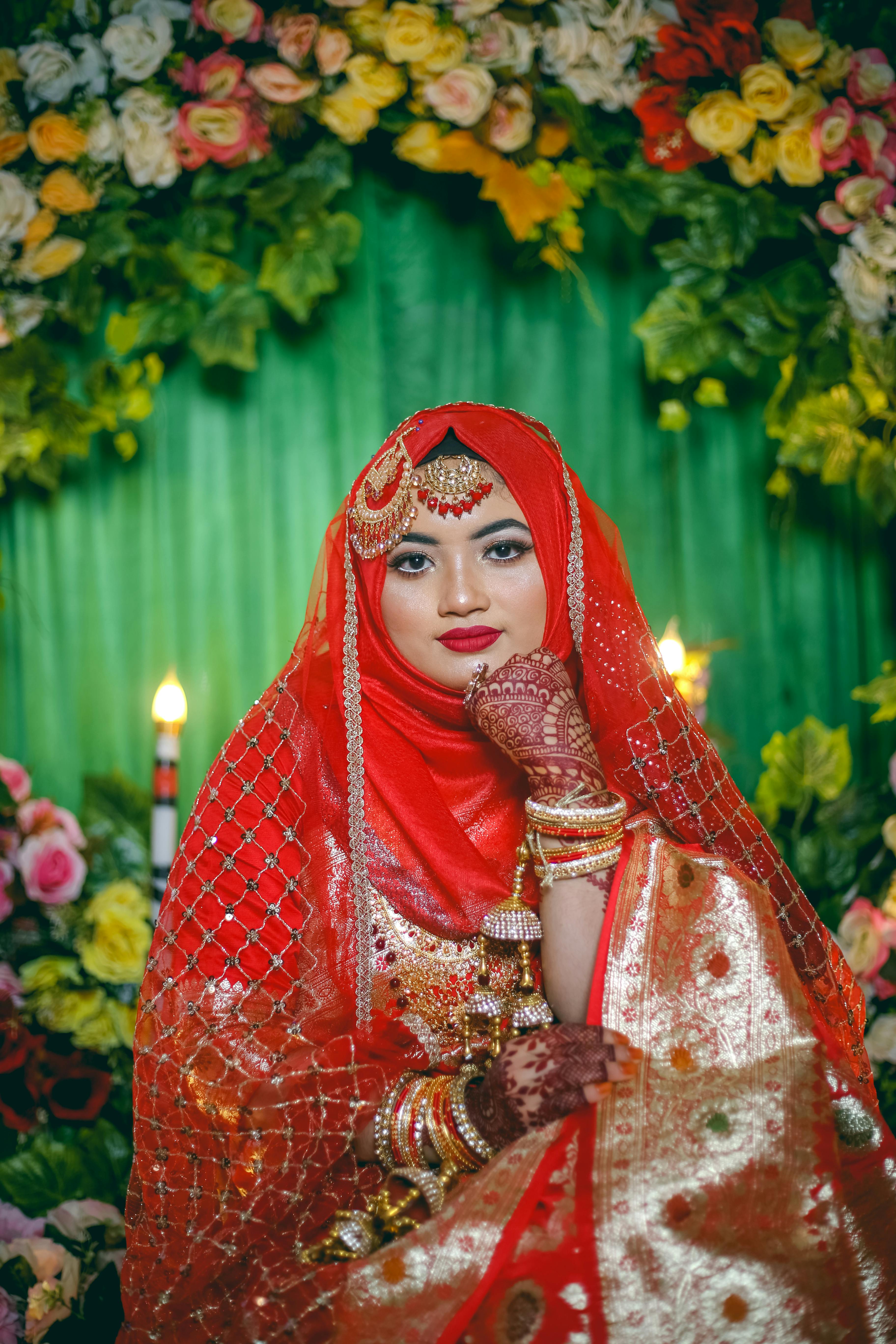 Indian bride in red lehenga embroidered with gold holds her hands with  henna tattoos on the knees during wedding ceremony Stock Photo | Adobe Stock