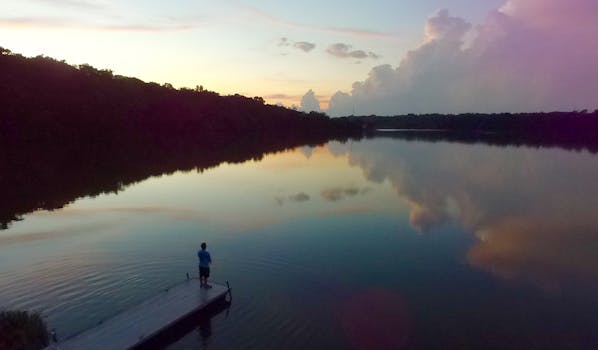 A peaceful sunrise scene with reflections on a calm lake.