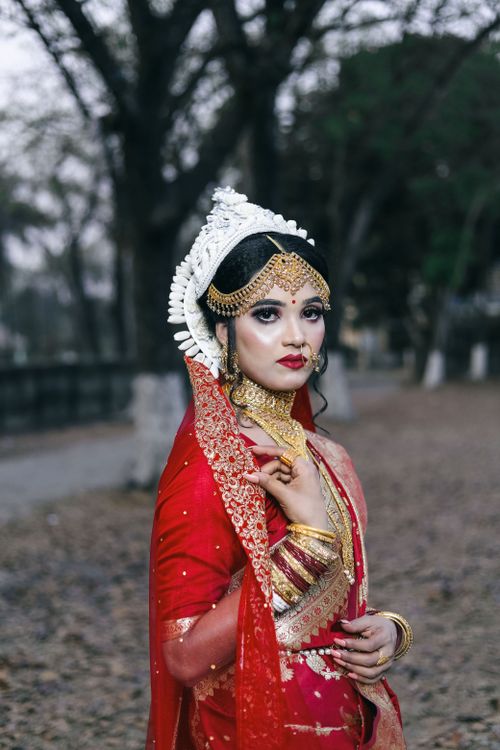 Free Elegant Indian bride adorned with traditional jewelry in vibrant red saree outdoors. Stock Photo