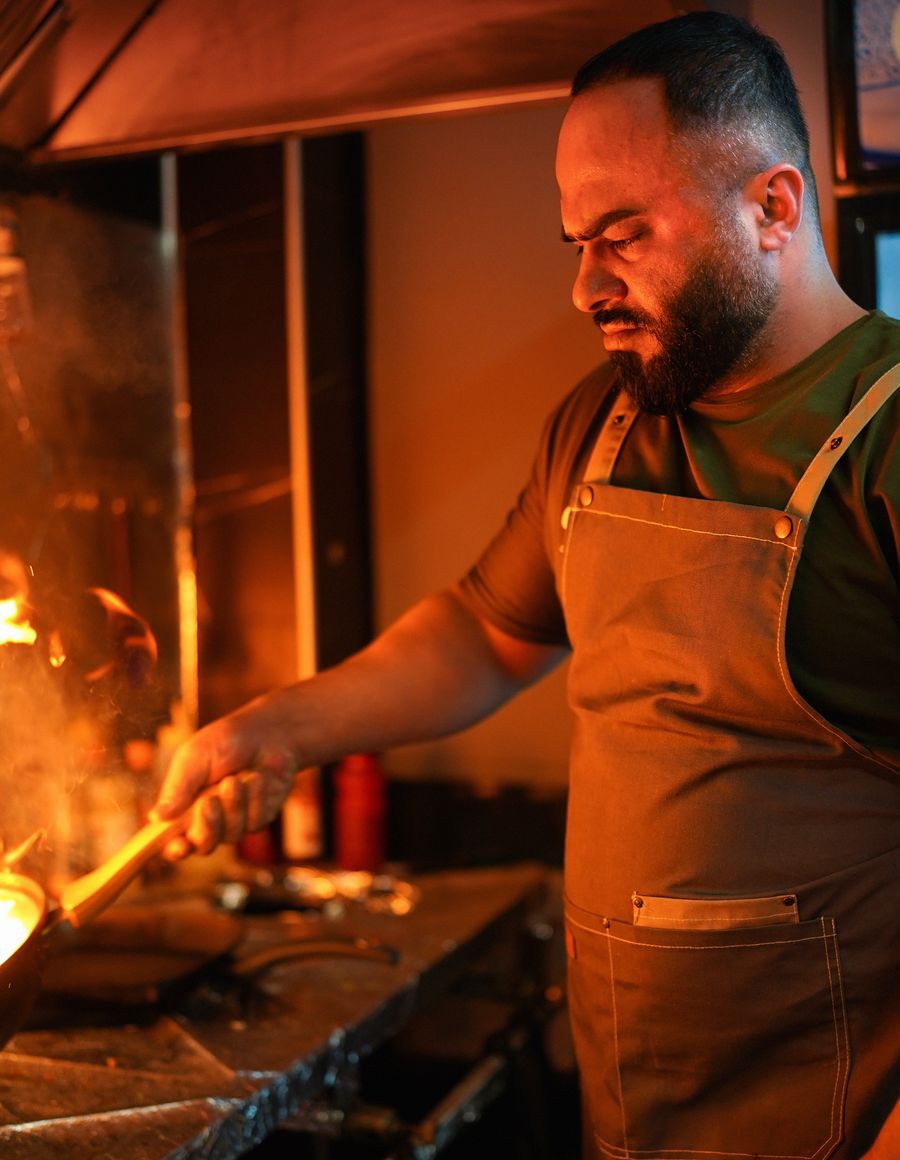 Cook in an apron working a flaming skillet