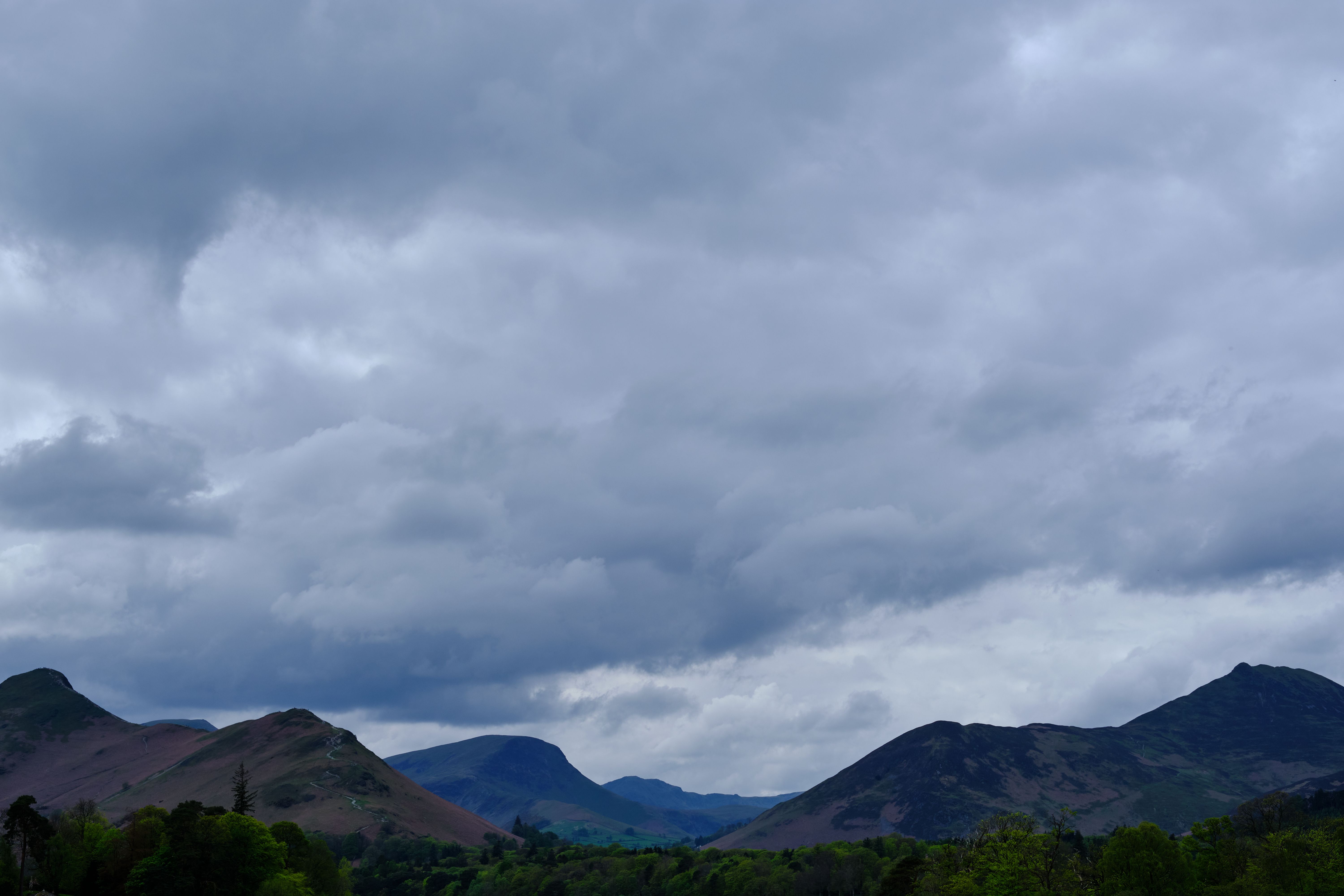 Overcast sky with dramatic clouds above a scenic mountain range in Keswick, England.