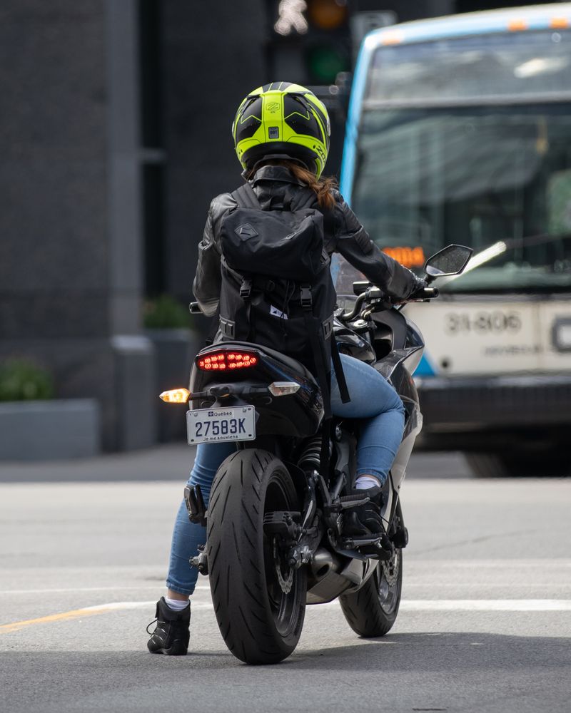 Motard casqué et en blouson attendant à un feu rouge en ville