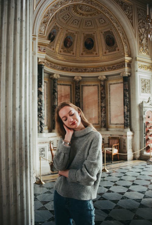 Woman in Gray Turtle-neck Sweater Near White Concrete Pillar