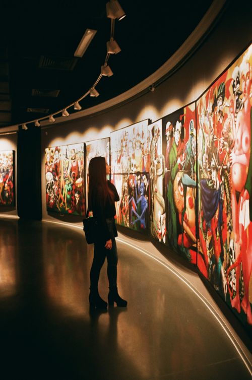 Free A woman observes vibrant paintings in an art gallery exhibition. Stock Photo