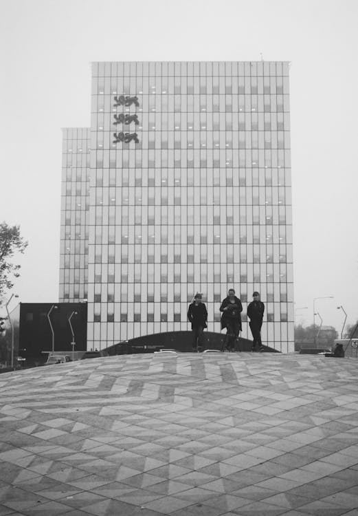 Grayscale Photo of Three People Near a Building
