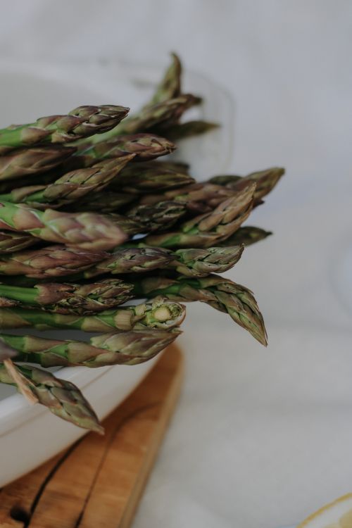 Free Close-up of fresh asparagus spears on a white ceramic plate, showcasing natural texture. Stock Photo