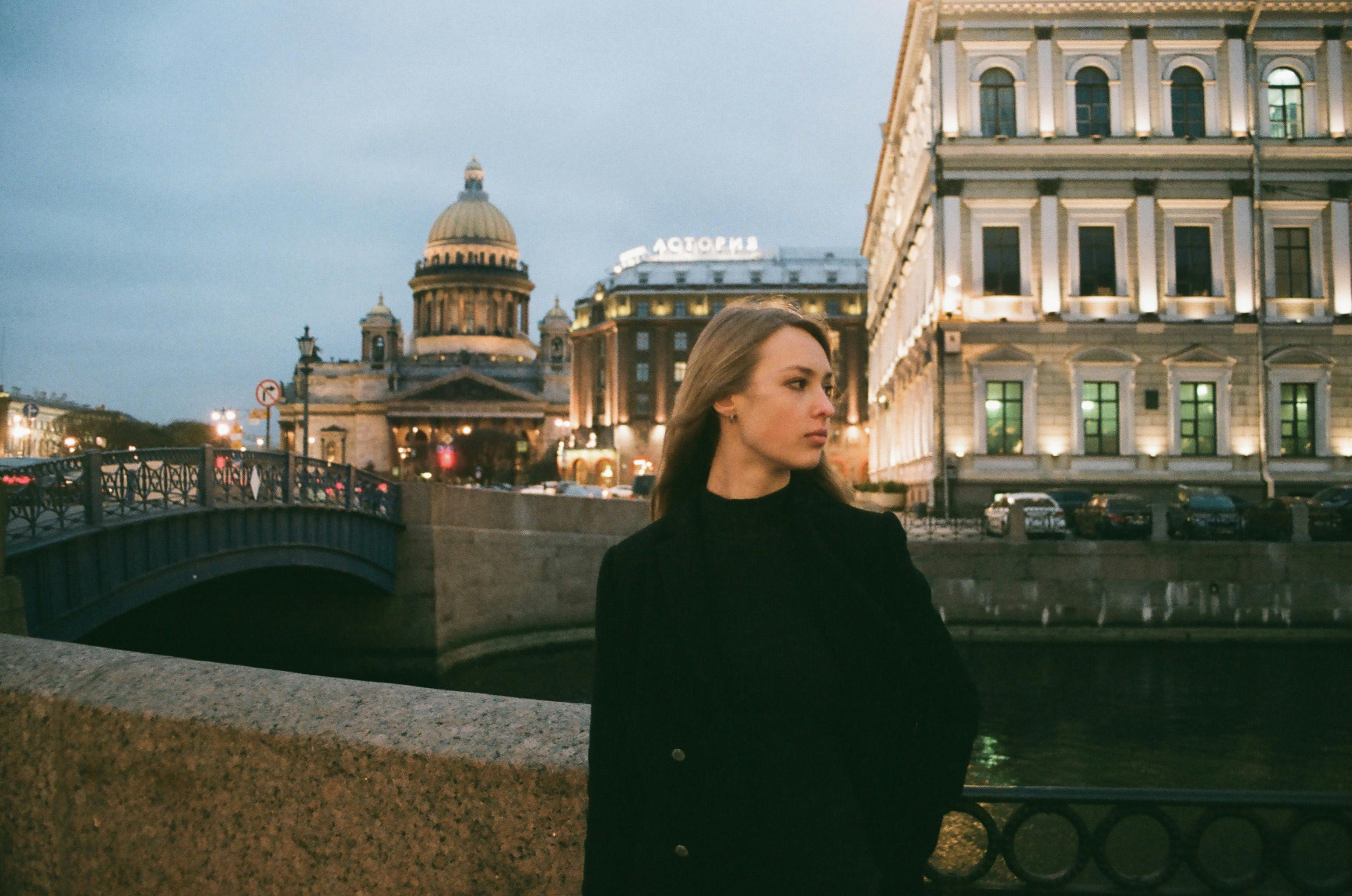 黄昏的灯光下，一名妇女站在圣艾萨克大教堂附近，展现出优雅的城市景观