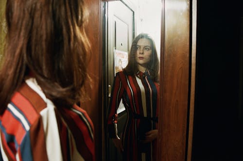 Woman Standing In Front Of Cabinet Mirror