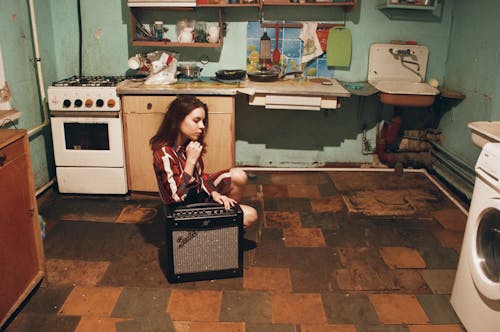 Fille Assise à Côté De L'amplificateur De Guitare Fender Gris Et Noir à L'intérieur De La Chambre