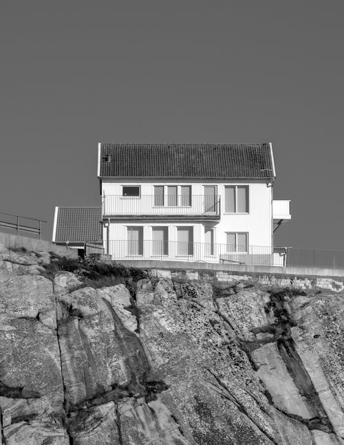 Black and White Photo of House Built on Rock