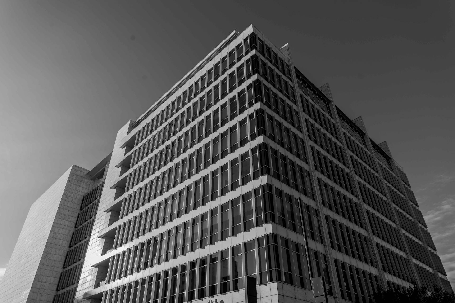 A dramatic black and white capture of a modern office building in an urban setting.