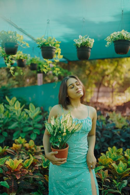 Free A serene portrait of a woman holding a potted plant in an outdoor garden setting. Stock Photo