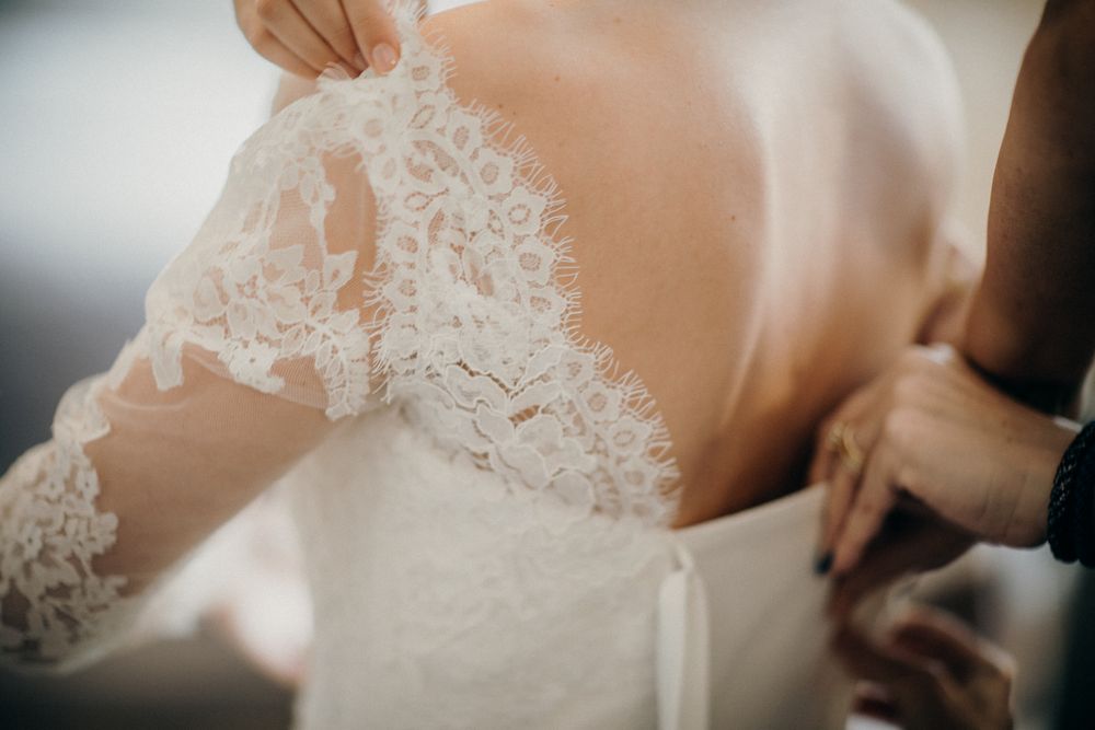 Close-up of a detailed lace wedding dress being carefully adjusted