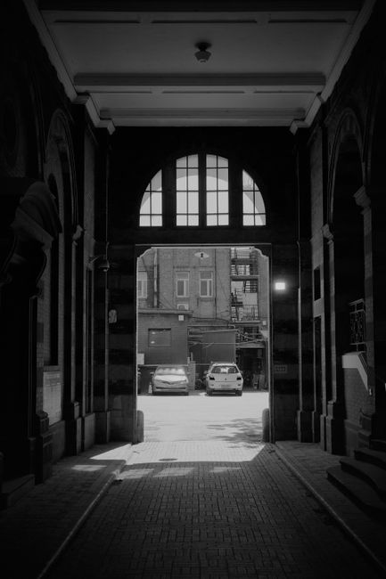 Moody black and white photo of a tunnel entrance in Tianjin, China, with cars outside.