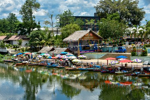 Free Vibrant waterfront scene with boats, umbrellas, and a lively market atmosphere. Stock Photo