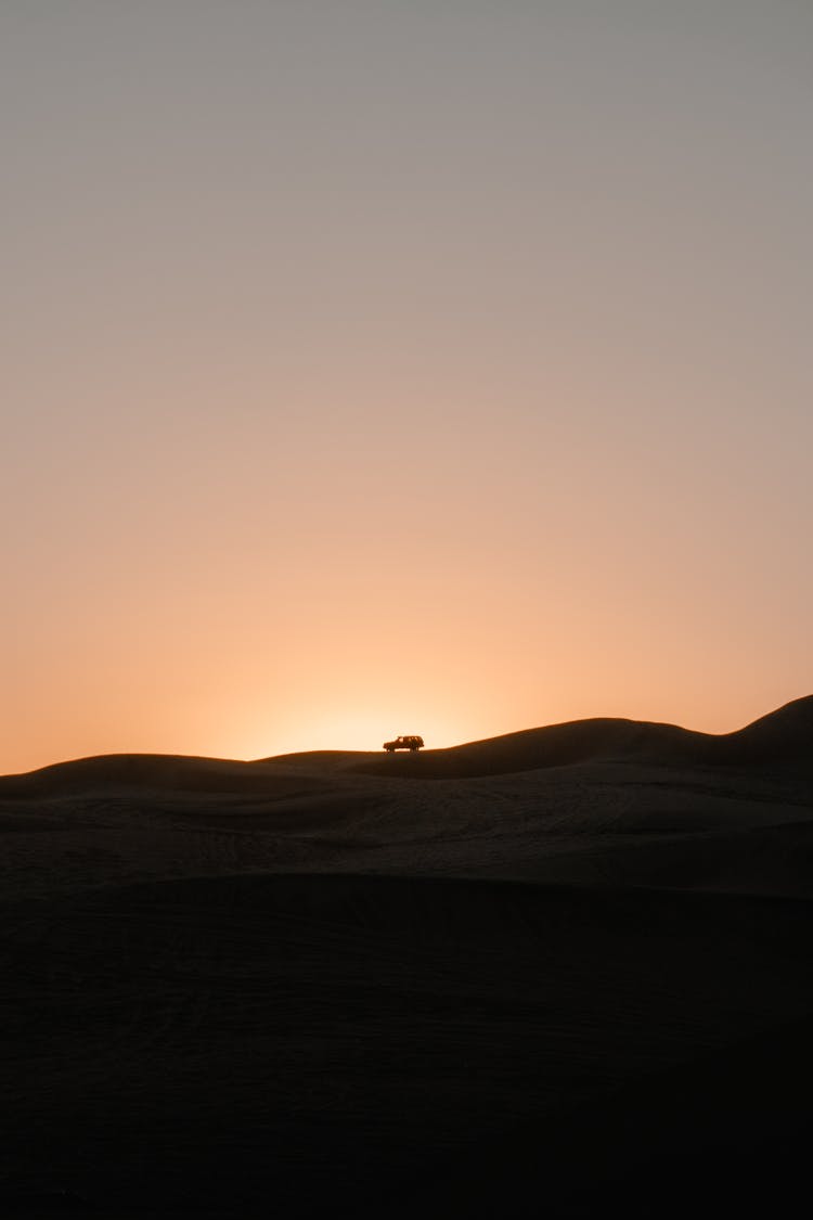 Silhouette Of A Car Riding On Top Of A Hill At Sunset 