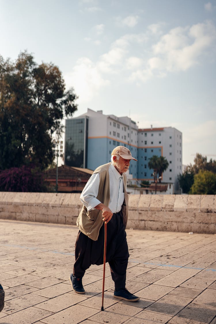 Senior Man Walking With A Stick On A Pavement