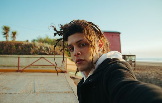 Young Man with Dreadlocks Taking a Selfie on the Beach 