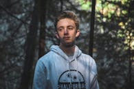 阳光明媚的森林中，一位穿着连帽衫的年轻人肖像展现了休闲时尚风格