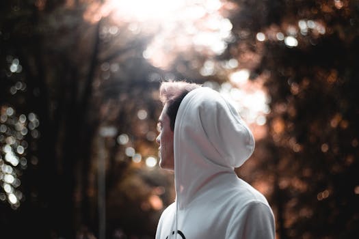 阳光下，一名穿着连帽衫的年轻人侧影，呈现出艺术散景效果