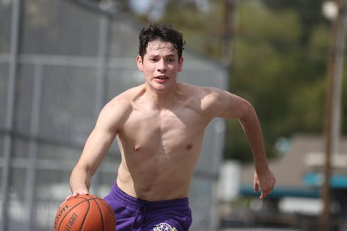 Shirtless Man Running and Bouncing a Basketball Ball 