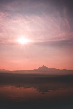 宁静的日落倒映在平静的湖水中，在山脉上勾勒出令人惊叹的轮廓