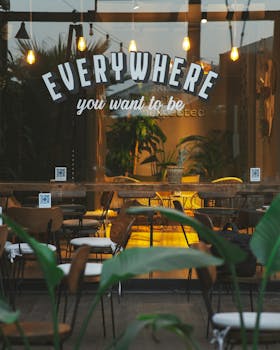 Inviting café exterior with modern ambiance, lush greenery, and warm lighting.