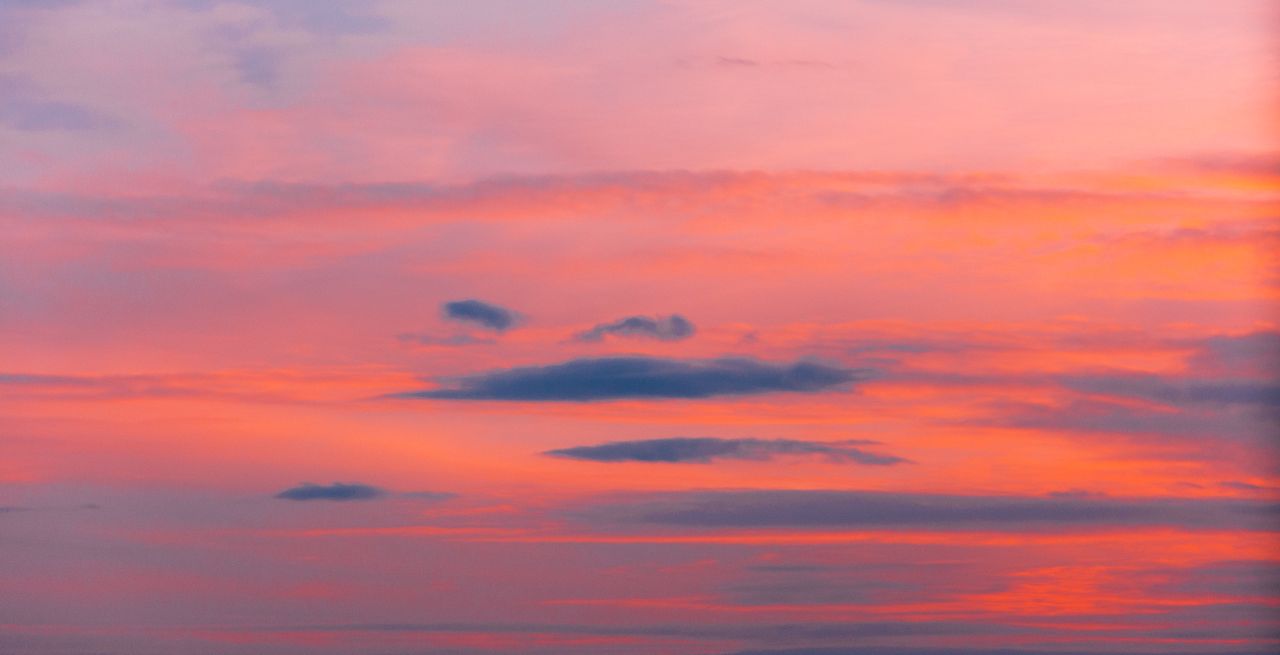 a stunning pink and orange sky during sunset with scattered clouds cre