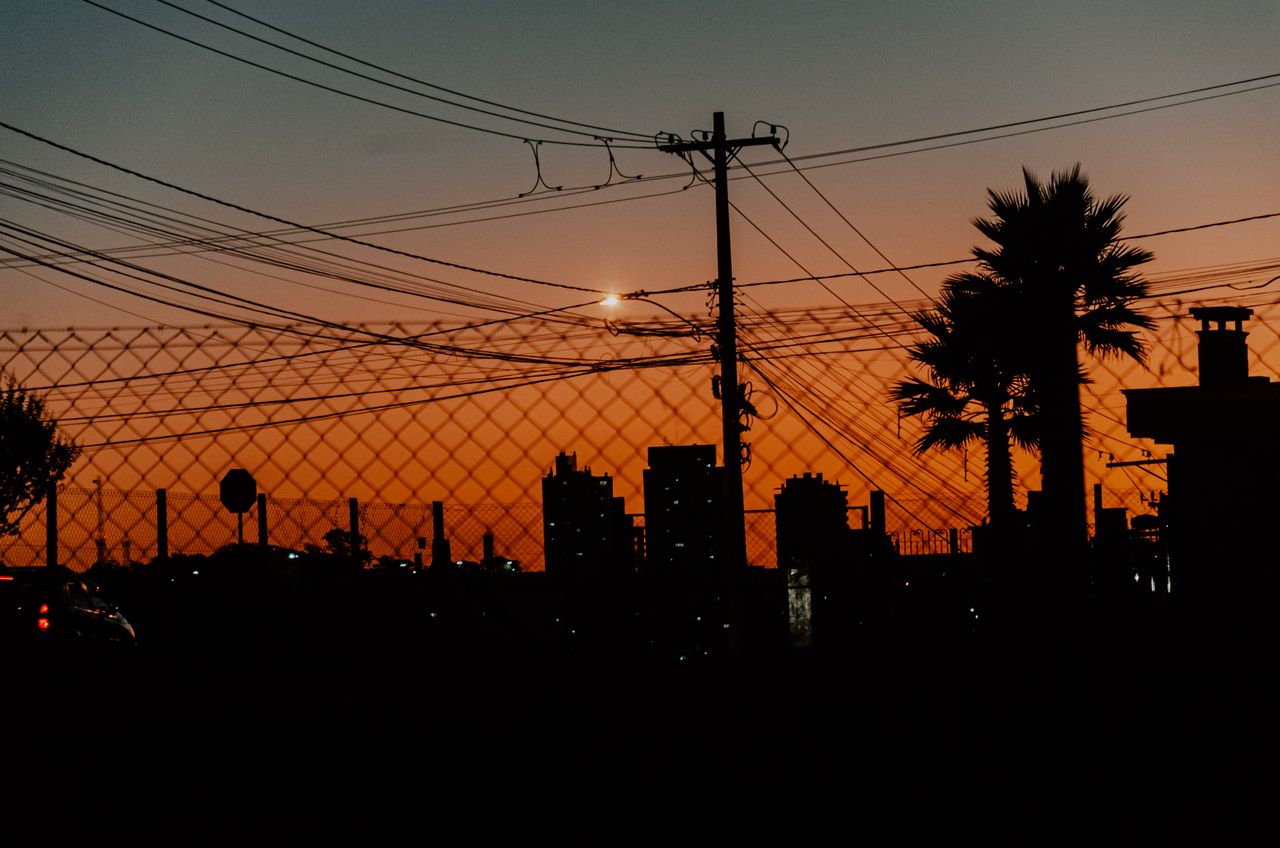 a dramatic urban sunset showcasing silhouettes of palm trees power lin