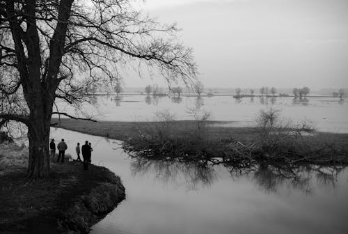 Black and white photo of people standing by the water
