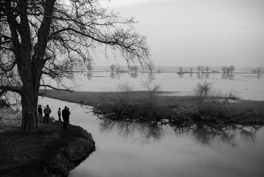 Black and white photo of people standing by the water