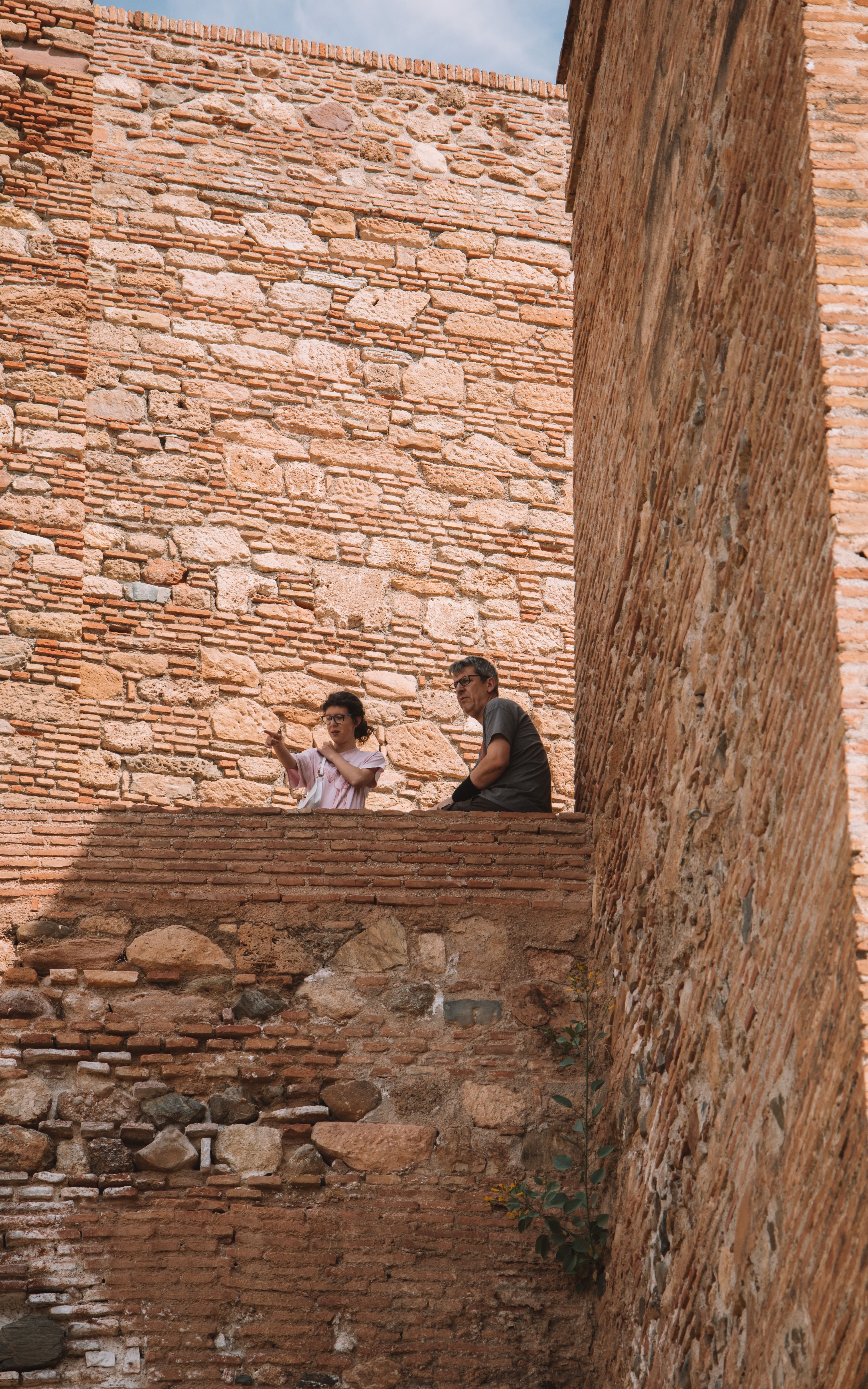A couple enjoying a summer day while sitting by an ancient brick wall, capturing memories.