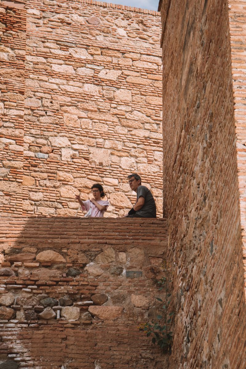 A couple enjoying a summer day while sitting by an ancient brick wall, capturing memories.