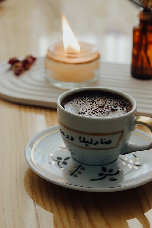 Close-up of a Cup of Coffee and a Candle in the Background 