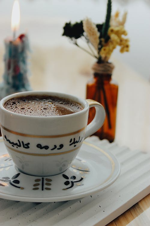 A Cup of Black Coffee, Flowers and a Candle on the Table 